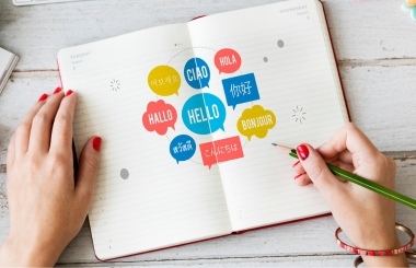 Hands writing diverse Spanish phrases in a notebook, demonstrating language acquisition through practice with special characters.