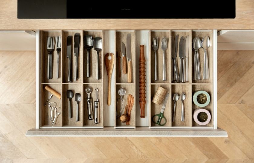 An organized kitchen drawer filled with an assortment of utensils, perfect for learning kitchen organization vocabulary in Spanish.