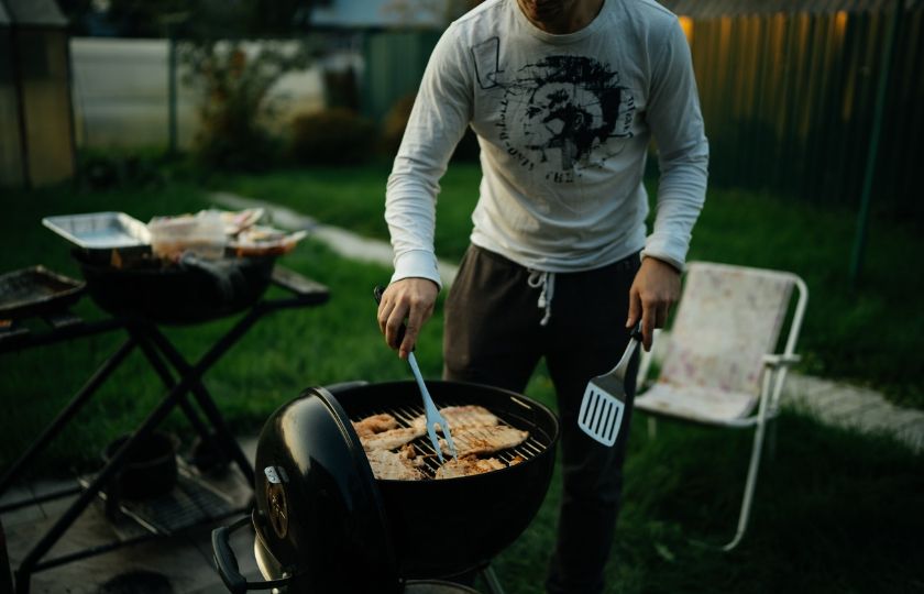 Man showcasing Spanish BBQ techniques in a backyard setting, ideal for learners of Spanish grilling terms.