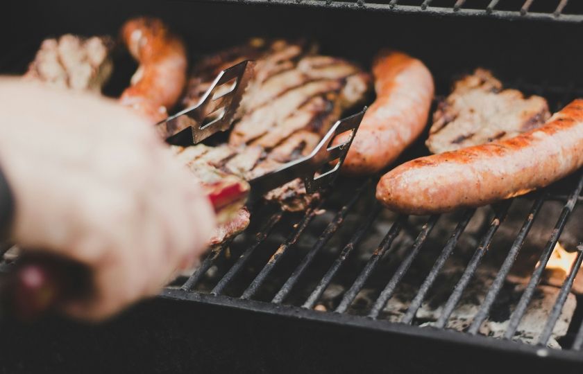 Grilled meats and sausages, a staple in Spanish BBQ vocabulary, sizzle on a grill.