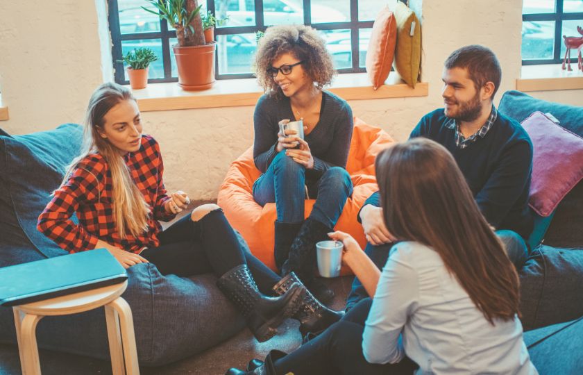 Four people sitting in a relaxed setting, engaged in casual Spanish conversation with slang