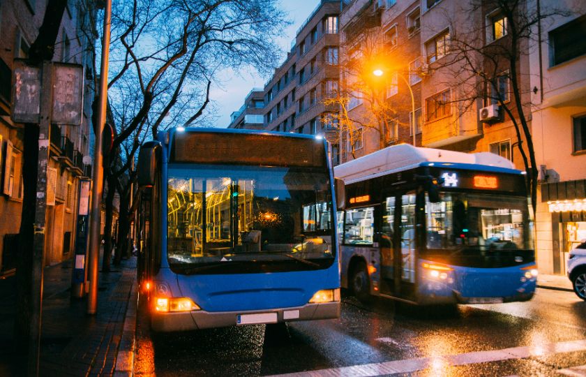 Two public buses on a city street in Spain, highlighting urban transportation for a Spanish vocabulary guide.