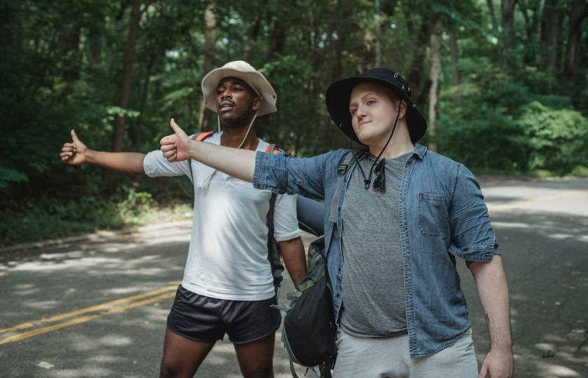 Two male travelers hitchhiking, highlighting the importance of knowing basic Spanish phrases for travel.