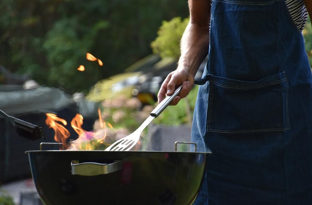 A person grilling food on a barbecue with a spatula.