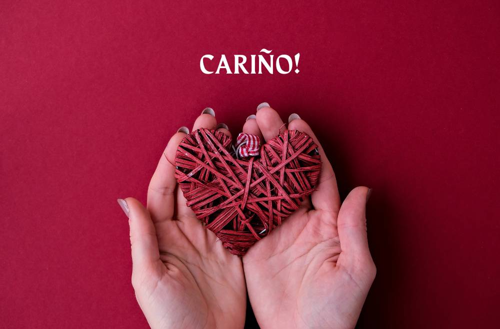 Hands delicately cradling a heart with the word 'Carino' written in the background, symbolizing love and affection.